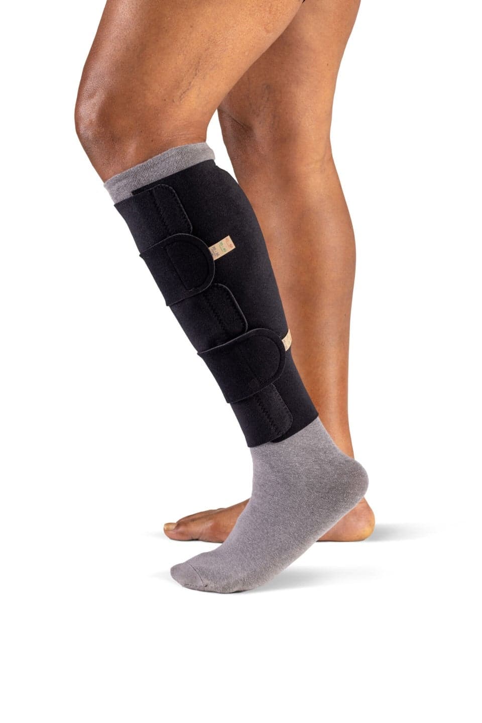 Faixa de compressão ajustável Sigvaris Compreflex Standard vestida na perna, com tiras de velcro, sobre fundo claro